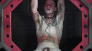 Pouring wax on the body of the tied, tattooed fella