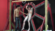 Pouring wax on the body of the tied, tattooed fella