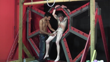 Pouring wax on the body of the tied, tattooed fella