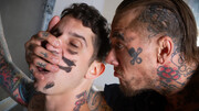 Dominant man with tattoos is having sex with a Latino