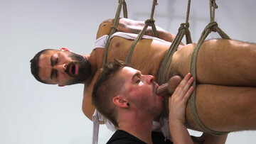 Adam Ramzi is tied up and hanging in the air while getting a BJ