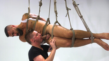 Adam Ramzi is tied up and hanging in the air while getting a BJ